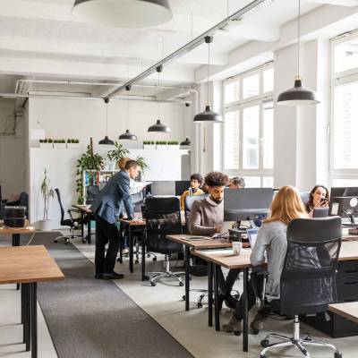 Employees sitting at their desks in an office doing and talking about work